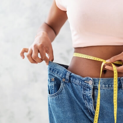 black-woman-in-old-big-jeans-measuring-her-waist-2023-11-27-05-10-52-utc